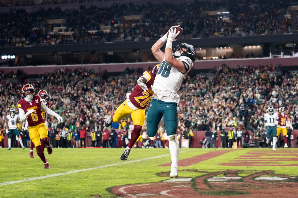 Dallas Goedert (88) completes a catch against Quan Martin (20) of the Washington Commanders for a touchdown during an NFL football game at Northwest Stadium on December 20, 2025 in Landover, Maryland. 