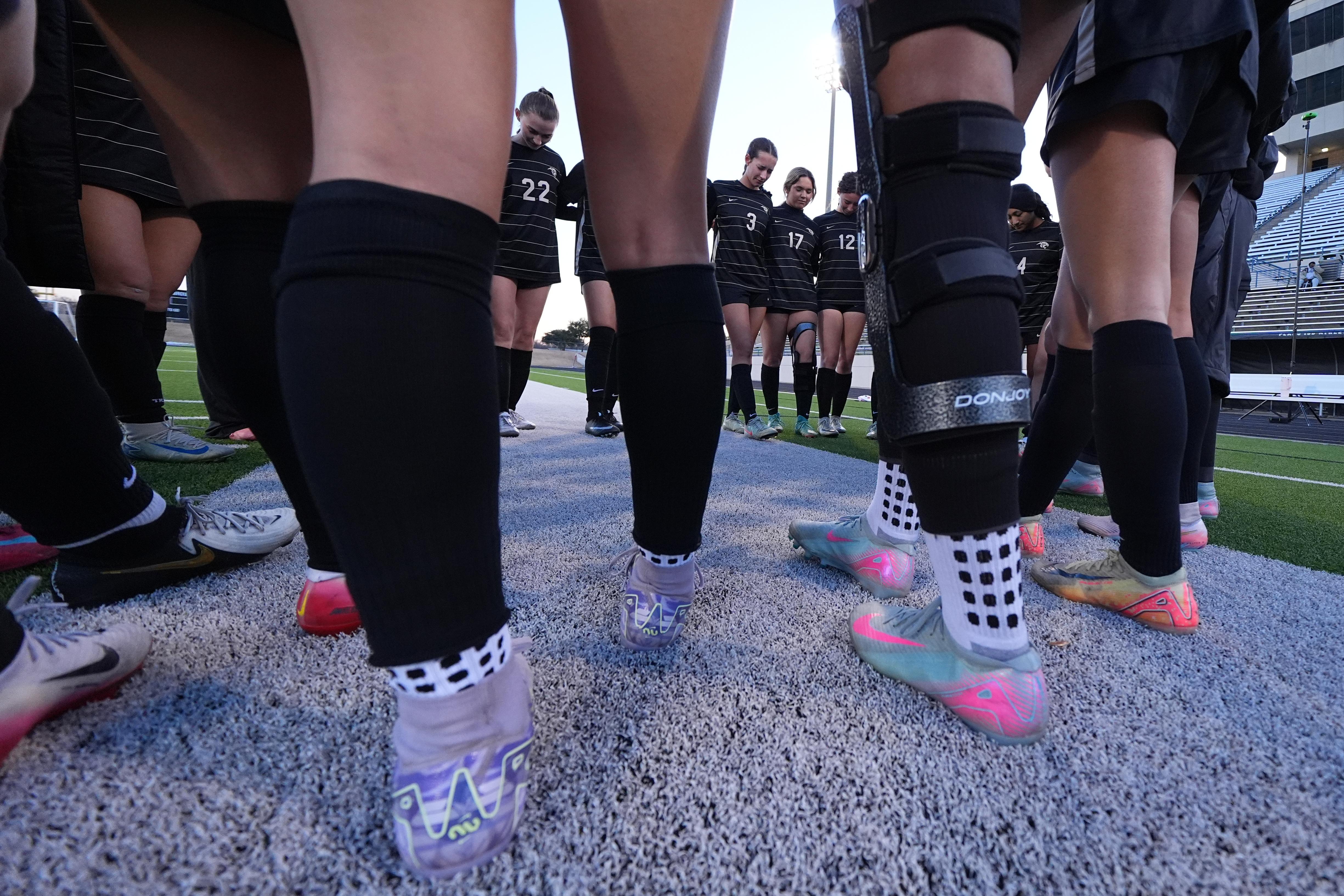 Aliya Jacob wears a knee brace as she gathers for prayer with teammates.