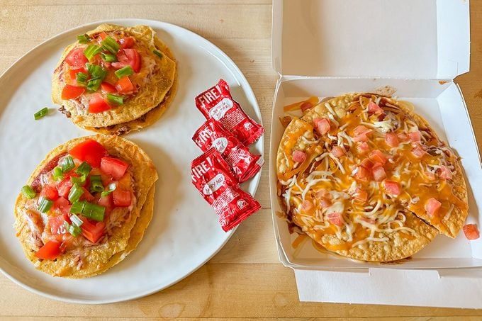 Prepared mexican pizza and few sauce packets place on a table, ready to eat