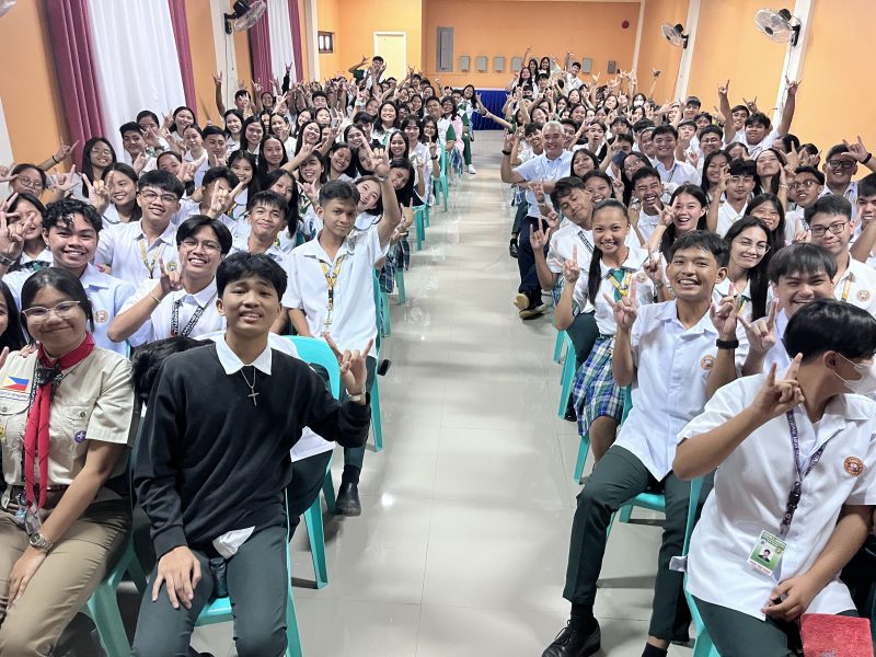 A room full of seated students throws up the Hook 'Em Horns hand sign.