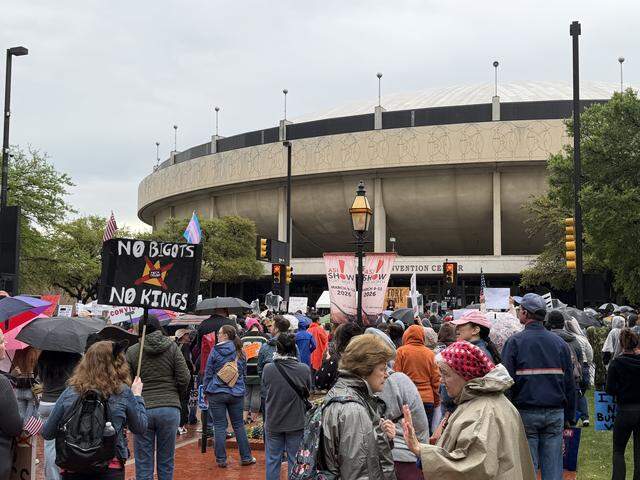 Protesters helds sign and participated in chants in front of the Fort Worth Convention Center on Saturday before taking off on a march during No Kings protests.