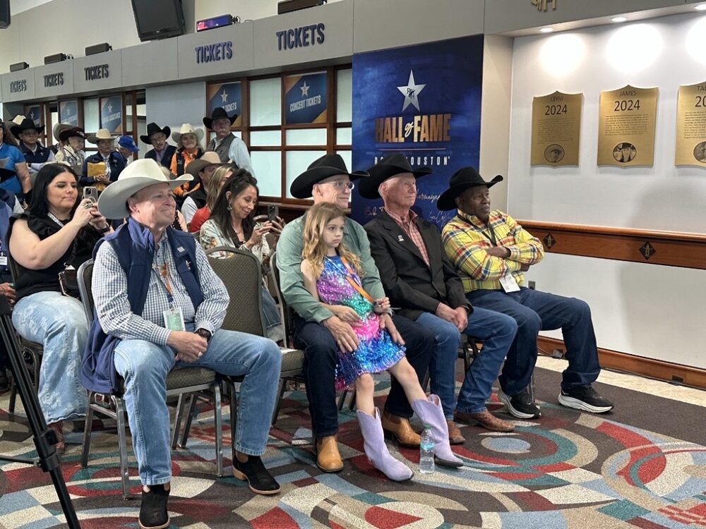 Champion bull rider Ty Murray (second from left) holds his daughter, Oakley, and sits next to Sammy Andrews, owner of the famous rodeo bull, Bodacious.