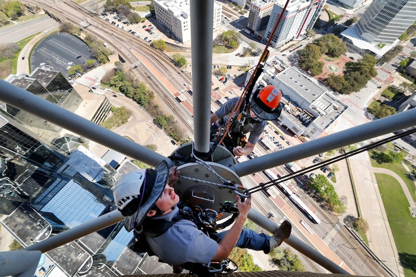 High above the railroad tracks at Union Station, rope access technicians Ian Porter (top)...