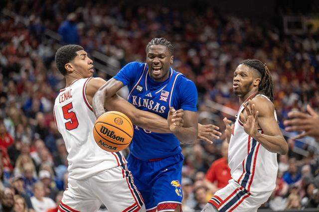Kansas Jayhawks forward Flory Bidunga (40) tries to grab the ball as Houston Cougars center Chris Cenac Jr. (5) and Houston Cougars guard Emanuel Sharp (21) defend in the first half at the Big 12 Men's Basketball Tournament at T-Mobile Center on Friday, March 13, 2026, in Kansas City.