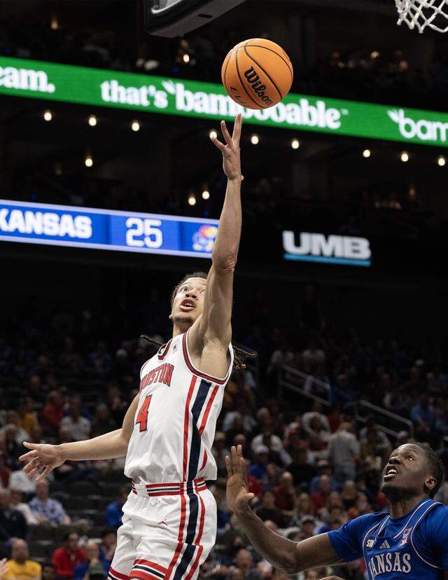 Houston Cougars guard Kingston Flemings (4) goes for the rim as Kansas Jayhawks forward Flory Bidunga (40) looks on during the second half at the Big 12 Men's Basketball Tournament at T-Mobile Center on Friday, March 13, 2026, in Kansas City. Houston defeated Kansas, 69-47.