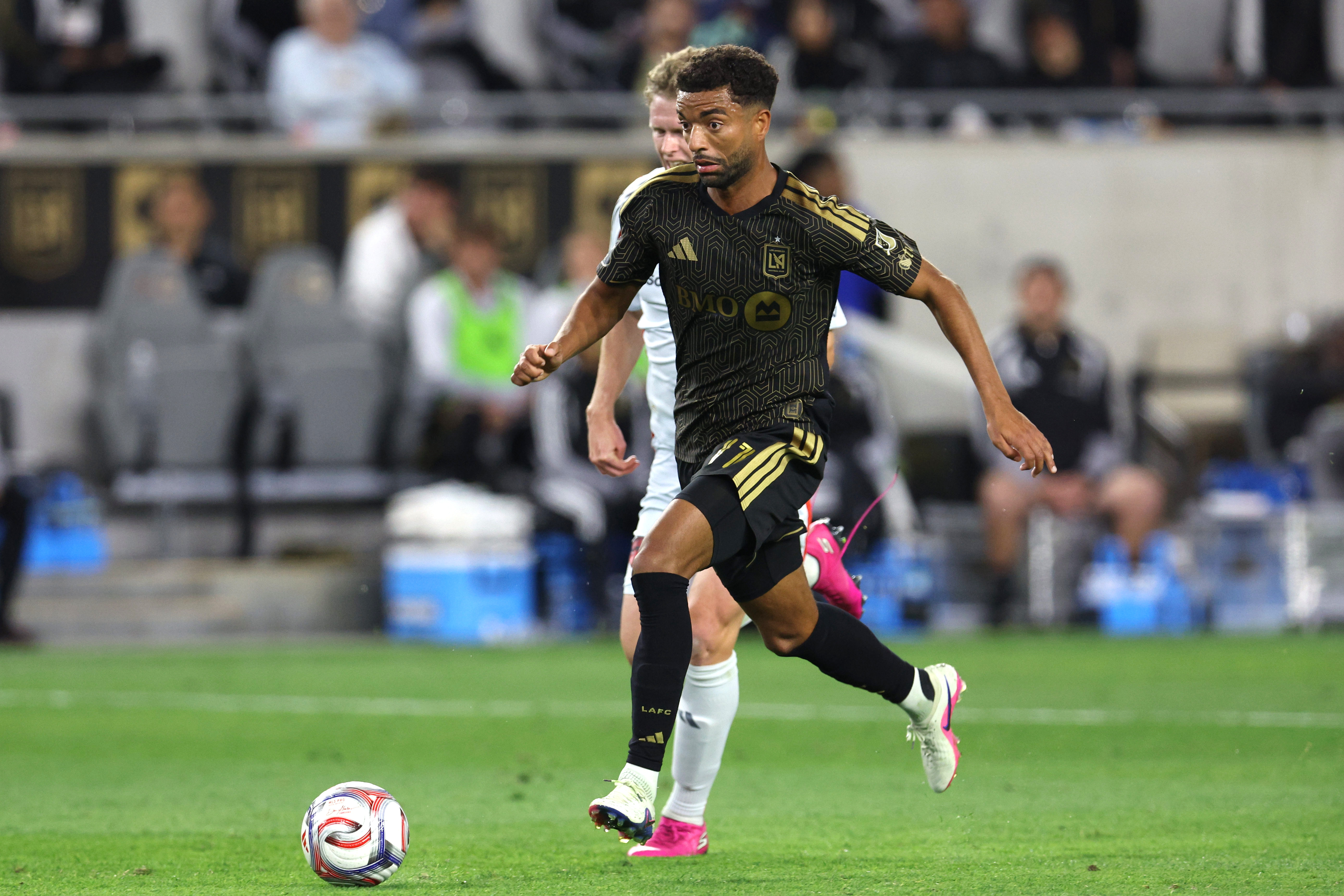 LAFC midfielder Timothy Tillman, front, kicks the ball downfield chased...