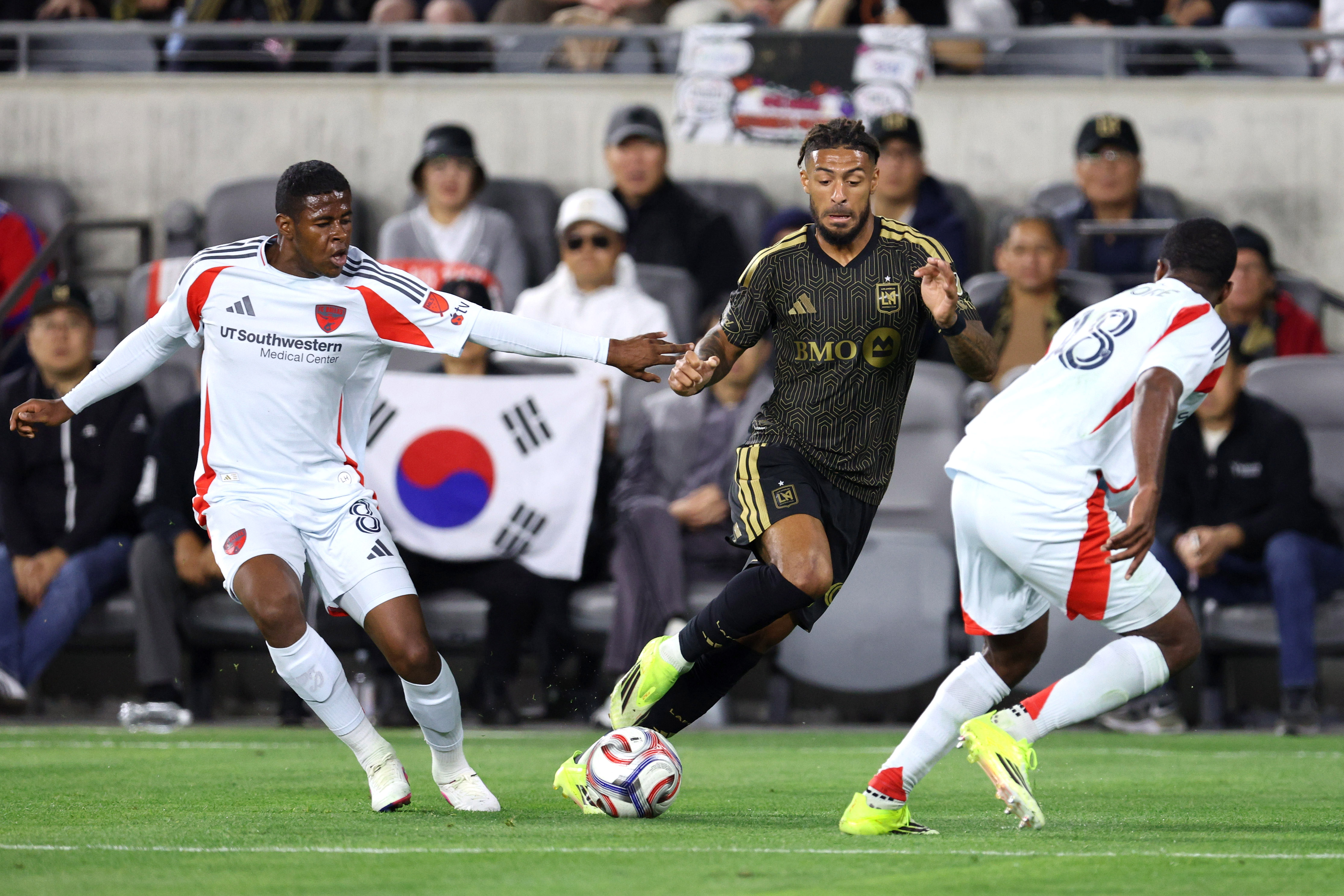 LAFC forward Denis Bouanga, center, moves the ball past FC...