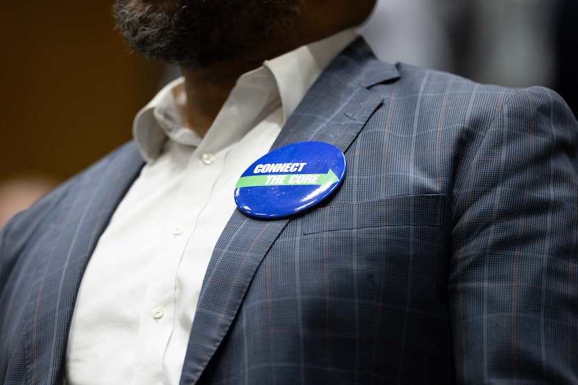 Audience members wear “CONNECT THE CORE” buttons during the open mic of a city council...