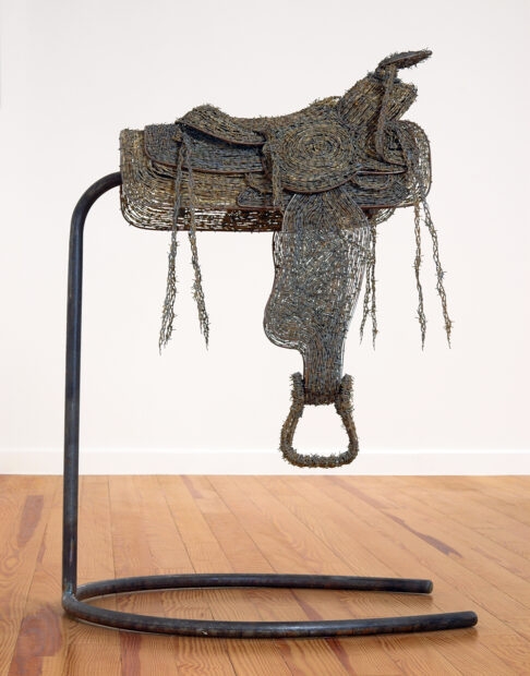 A photograph of a sculpture of a saddle made with barbed wire and steel by Mel Chin.