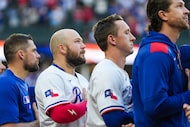 Texas Rangers first baseman Jake Burger (second from left) stands for the national anthem...