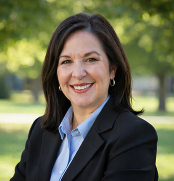 Nancy Ochs wears suit jacket and smiles outside.