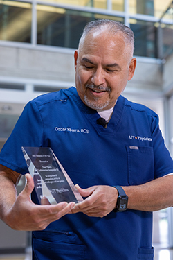 Oscar Ybarra, triple crown winner, stands looking at his award.