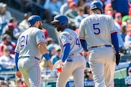 Texas Rangers' Andrew McCutchen, center, celebrates his three run home run with Jake Burger...