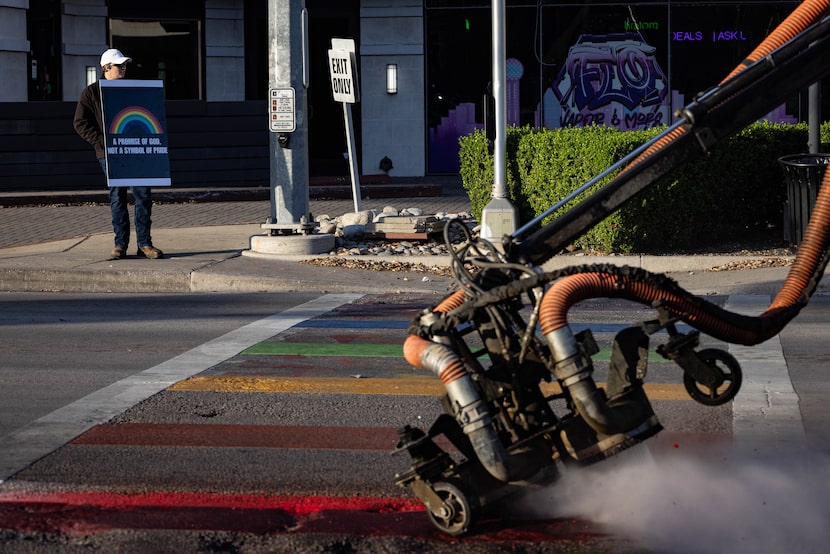 A man holds a sign with a rainbow that says “A promise of God, not a symbol of PRIDE” as a...