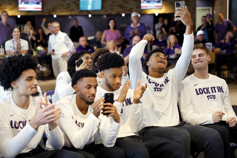 The TCU men’s basketball players, including Micah Robinson (second from right) react to...
