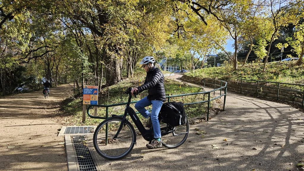 A person wearing a black jacket and helmet riding a bike on a paved trail