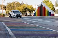Cars drive past a rainbow crosswalk at the intersection of Cedar Springs Road and Oak Lawn...