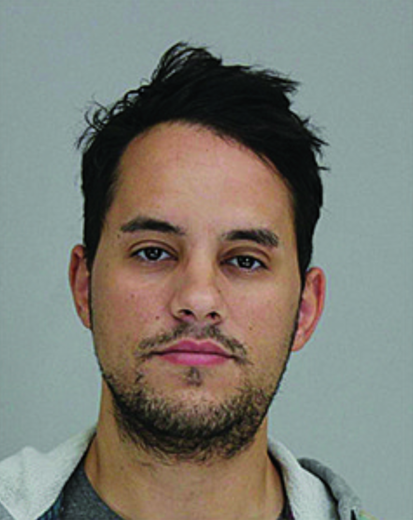Mugshot of a man with dark hair and a beard, wearing a gray hoodie.