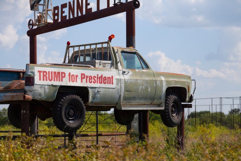A "Trump for President" sign hangs on the side of a rusted pickup truck in rural Texas.