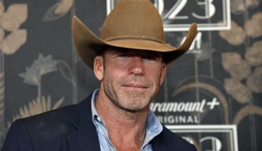 Taylor Sheridan wears brown cowboy hat in front of press step and repeat for paramount plus