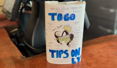 A brightly colored to-go tip jar on a counter of a restaurant.