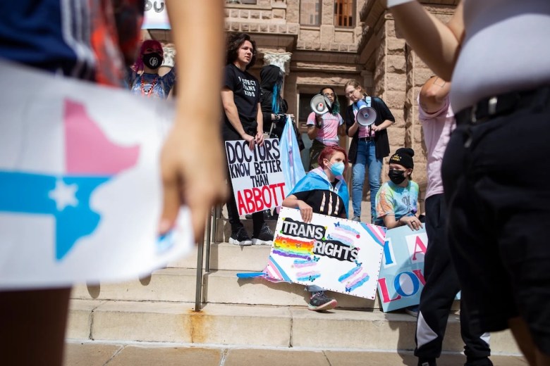 People hold signs in front of the Texas Capitol during a protest for transgender kids' rights on Mar. 1, 2022.