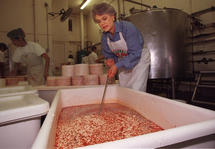 (Left to right) Octavia Flores stacks molds while Paula Lambert stirs a vat of curds with...