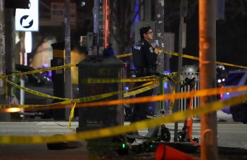 An Austin police officer works at the scene on West Sixth Street after a shooting outside...