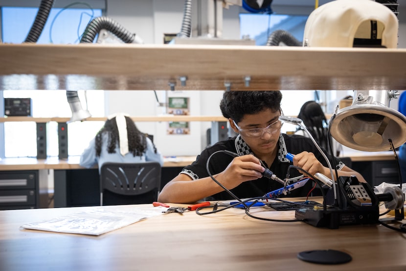Electronics student Emerson Cortez uses a soldering iron to disassemble a chip at Dallas...
