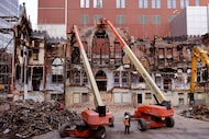 Demolition crews remove parts of the three point arch at the top of a crumbling north wall,...