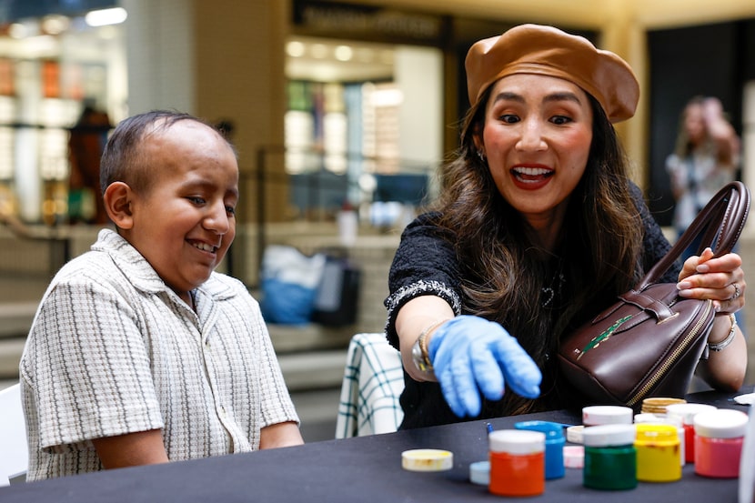 Artist Sharon Lee Clark helps pediatric patient model Liam Yoel Eugenio Lara, 12, paint a...