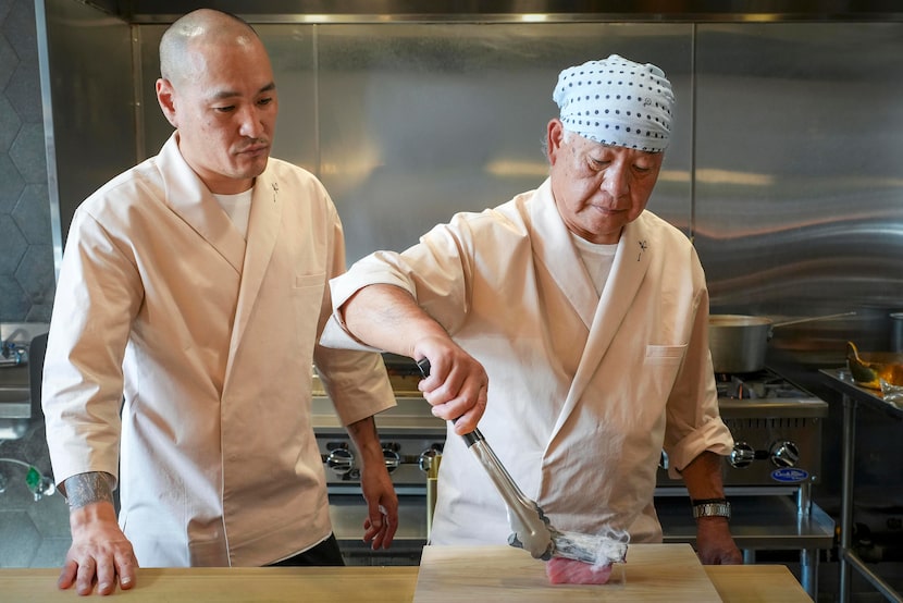 Chef Chikao Kikuchi sears sashimi with charcoal as chef Leo Kekoa looks on at Ichika on...