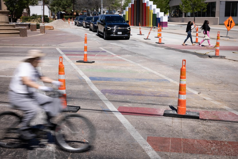 A cyclist rides past construction and a rainbow crosswalk at the intersection of Cedar...