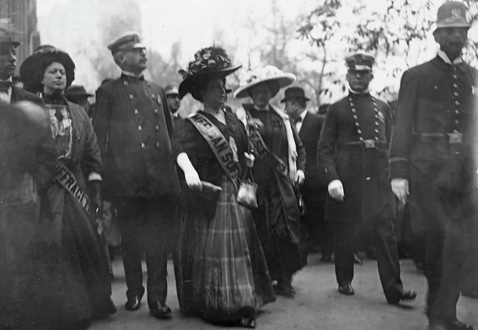 American actress Trixie Friganza with suffragists, weairng an 'America Suffragettes' sash, escorted by police officers after a women's suffrage rally outside New York City Hall in New York City, Oct. 28 1908. (Photo by Paul Thompson/FPG/Archive Photos/Hulton Archive/Getty Imag (Paul Thompson/FPG/Hulton Archive via Getty Images)