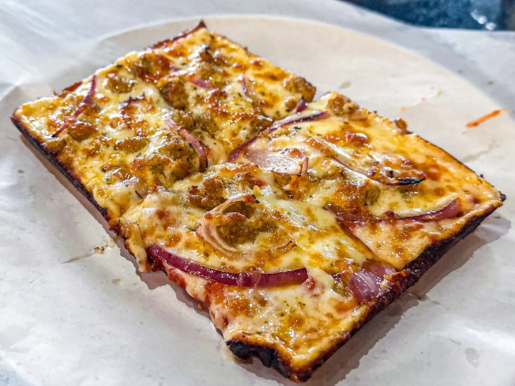 A close up of a slice of pizza from Andrew's American Kitchen Pizza 