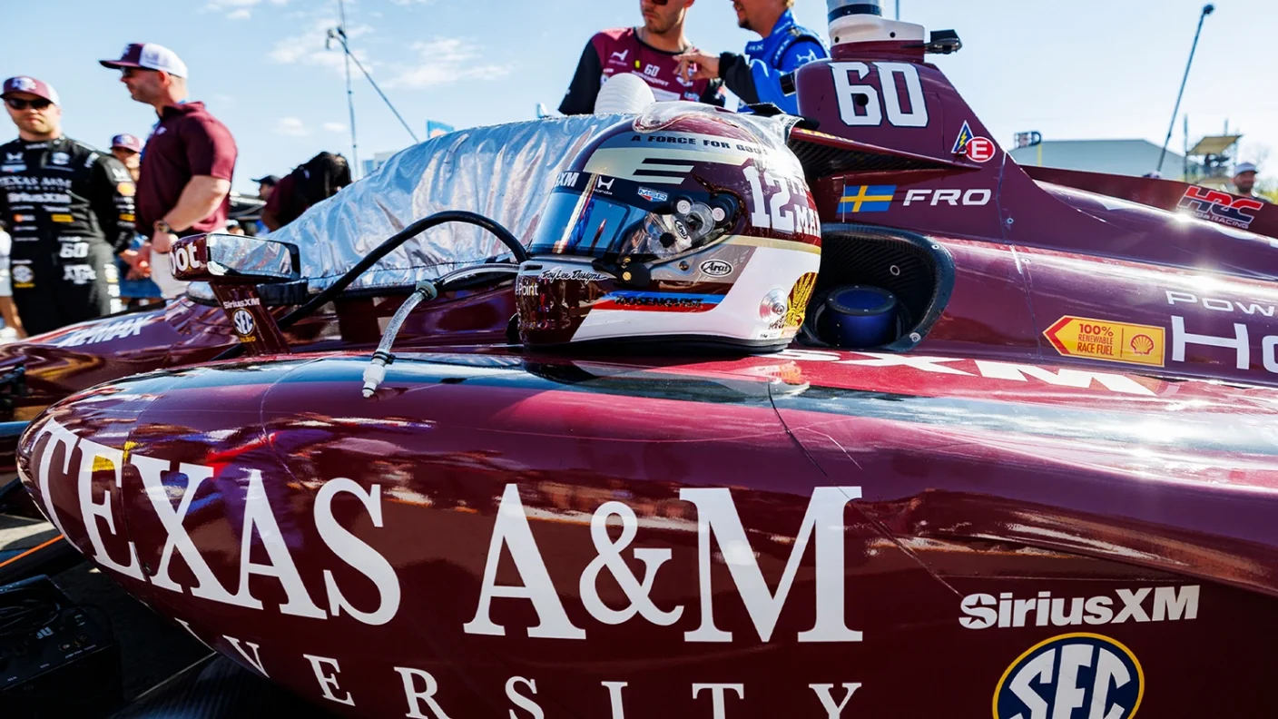 A race car helmet sits on a Texas A&M-branded race car