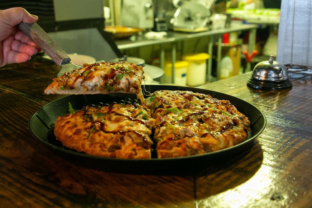 Leah Pezzi, a manager at Padre Pizzeria, pulls a slice from a barbecue pizza on Feb. 9, 2023.