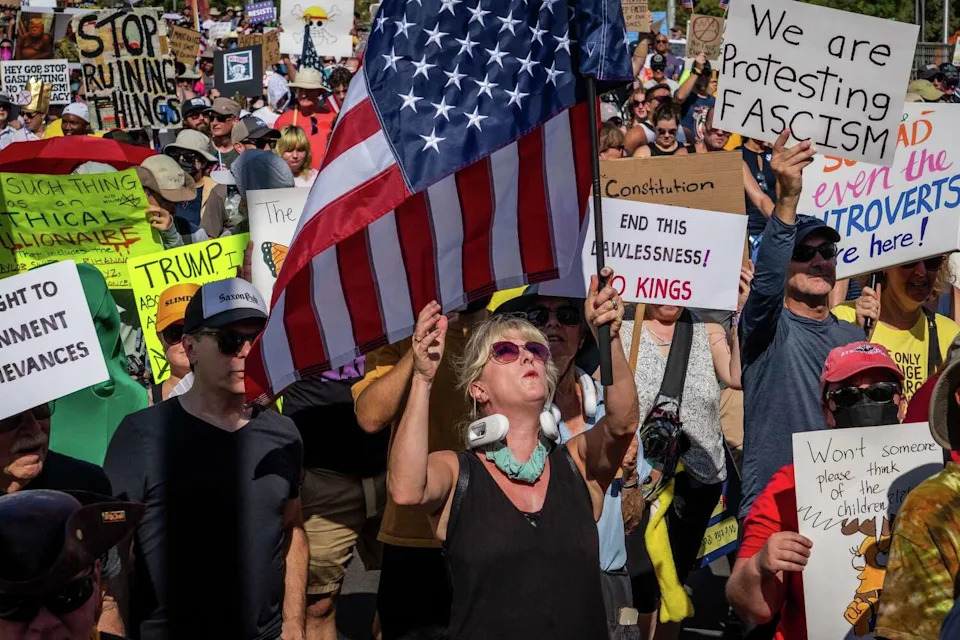 A woman adjusts her American flag as she marches with thousands of other protesters through downtown Austin for the No Kings rally, Oct. 18, 2025. The rally against President Donald Trump and his policies included speakers, a march from the Texas State Capitol to Auditorium Shores and live music and occurred in conjunction with others across the country. (Sara Diggins/Austin American-Statesman)