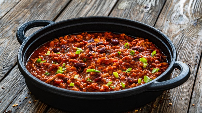 Chili con carne in cast iron pan on wooden table