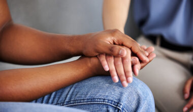 tight cropped photo of someone holding hands of another on their lap