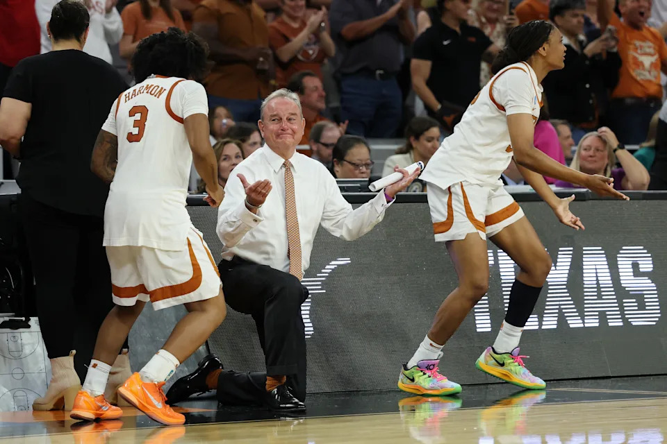 FORT WORTH, TEXAS - MARCH 30: Rori Harmon #3, head coach Vic Schaefer, and Madison Booker #35 of the Texas Longhorns celebrate in the fourth quarter against the Michigan Wolverines in the Elite Eight of the 2026 NCAA Women's Basketball Tournament at Dickies Arena on March 30, 2026 in Fort Worth, Texas.  (Photo by Elsa/Getty Images)