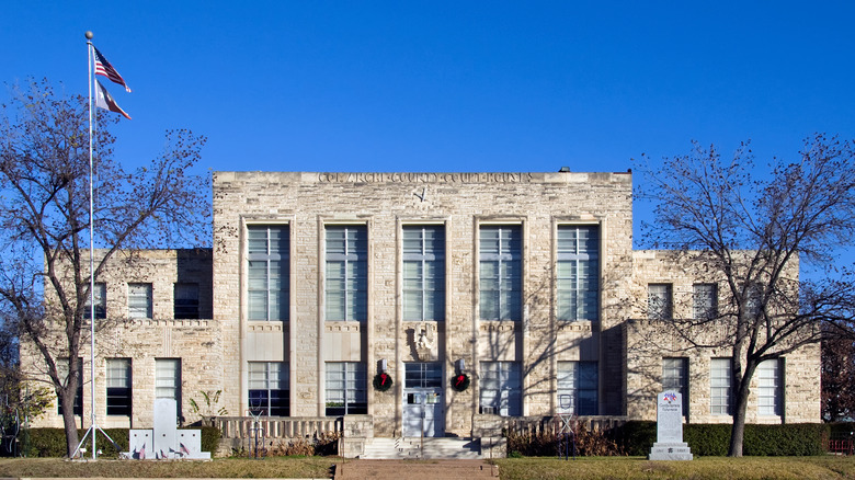 Stone building with tall glass windows set against a clear blue sky, Comanche modern courthouse, Texas
