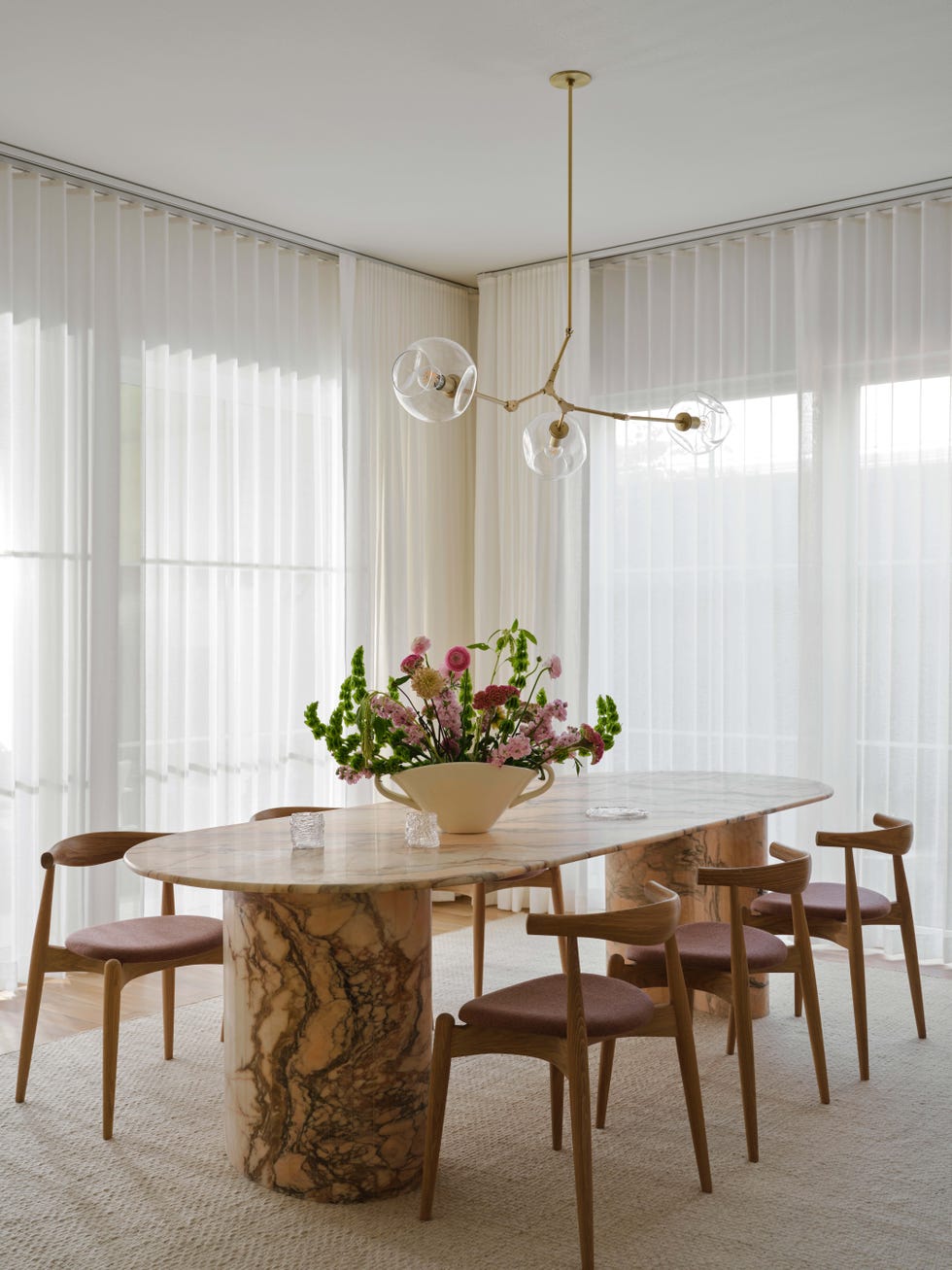 Modern dining area with a marble table and floral centerpiece.