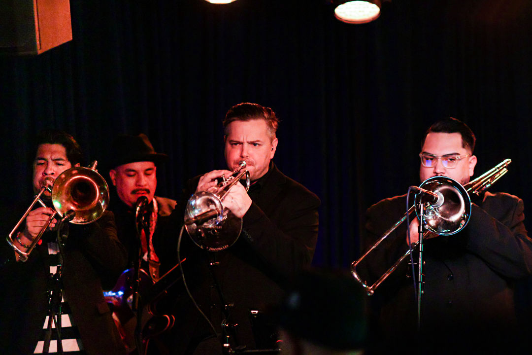 A ska horn line performing on stage.