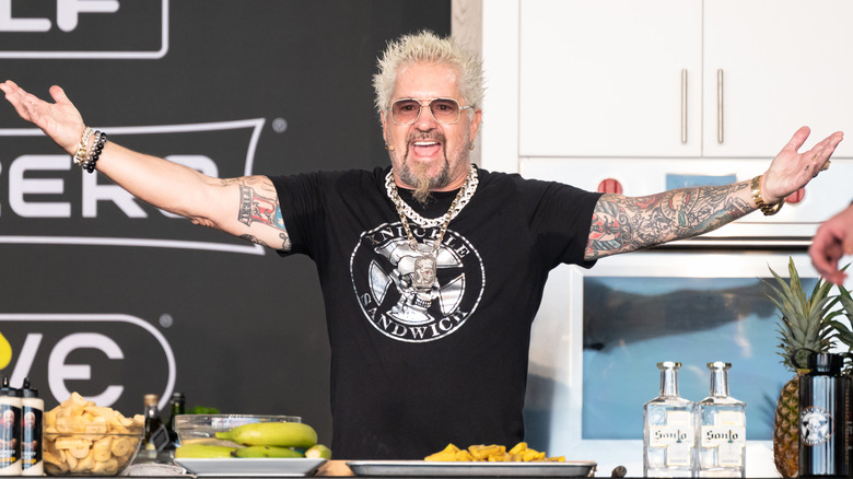Guy Fieri with his arms wide open at a cooking demo