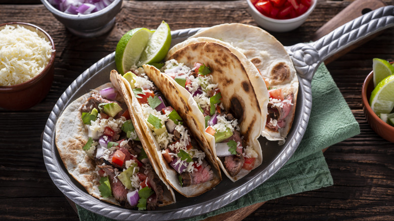 A shot of three steak tacos in flour tortillas