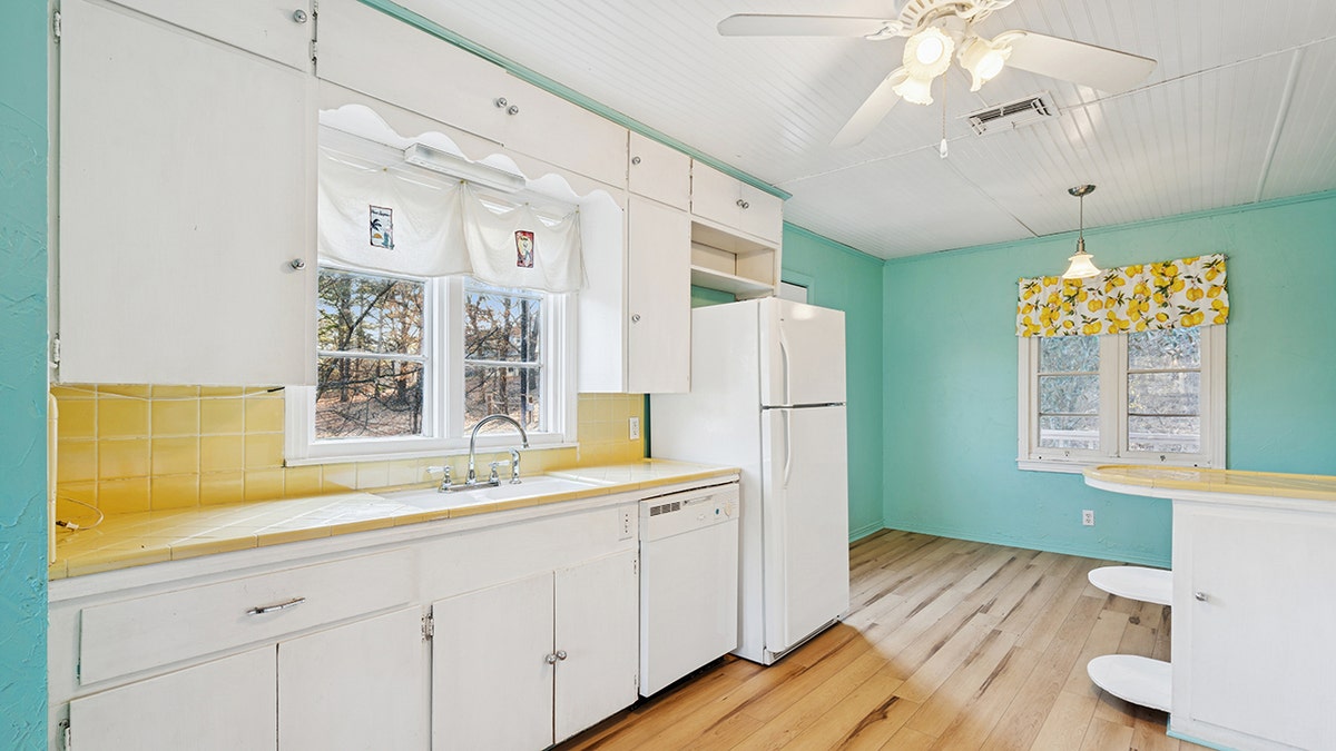 The kitchen in the pink house has blue walls and white cabinets.