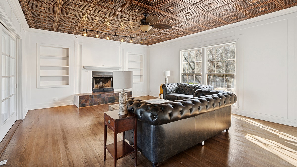 The living room features designs on the ceiling and a fireplace,