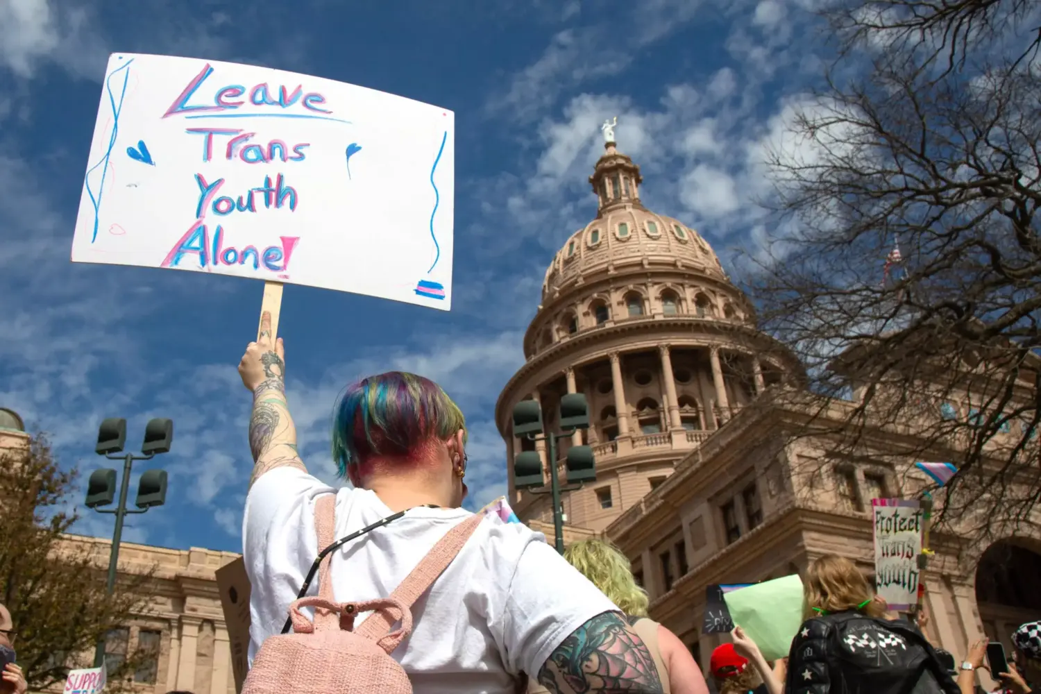 Demonstrators hold signs in support of transgender youth and rights in response to recent proposed legal action against parents seeking gender affirming healthcare for their children to be charged as child abuse at the Rally for Trans Youth at the Texas State Capitol on Mar. 1, 2022.