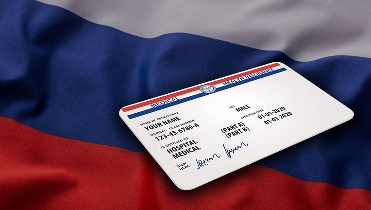 An image of a Medicare card over the Russian flag in the background. (Adobe Stock)